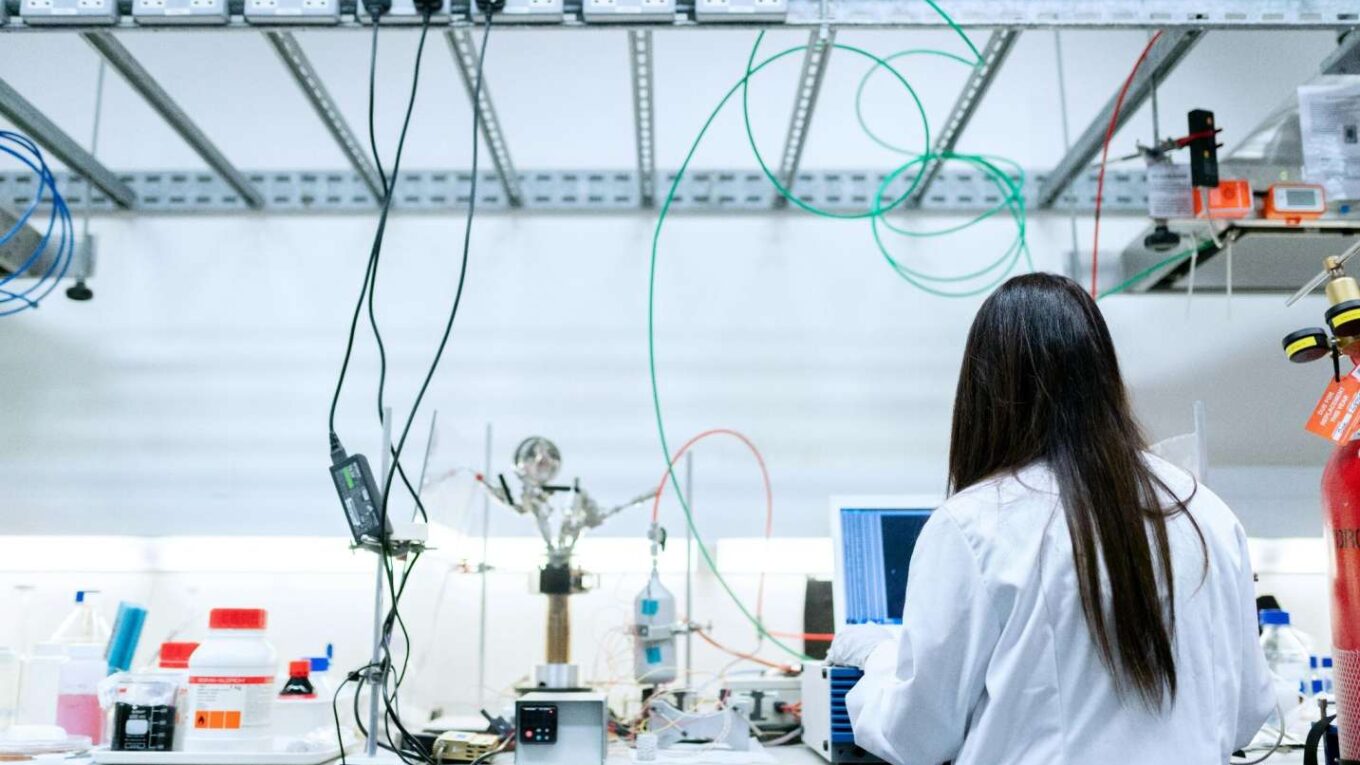 A woman intently working on a computer in an industrial environment.
